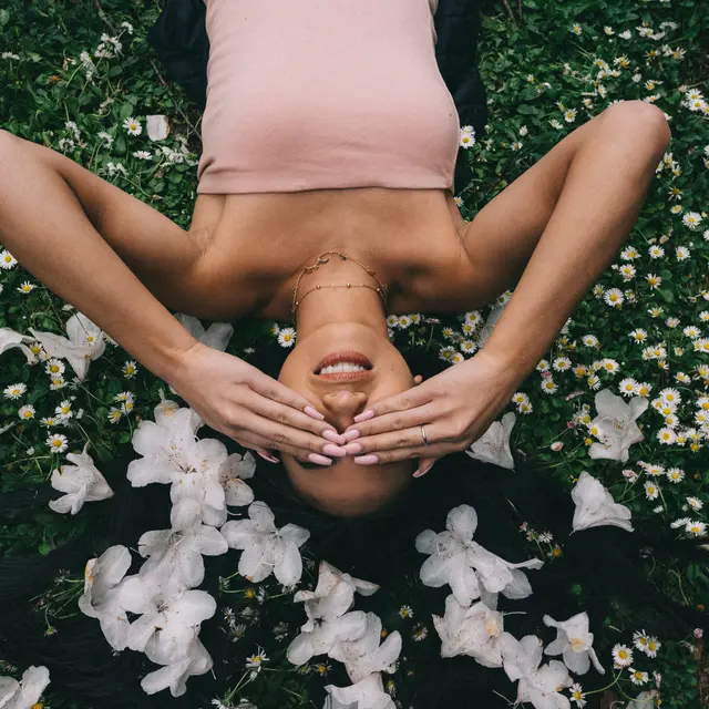 beautiful-model-laying-field-with-white-flowers