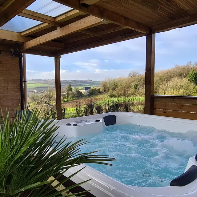 Jacuzzi sous pergola avec panorama sur la vallée de la Hem