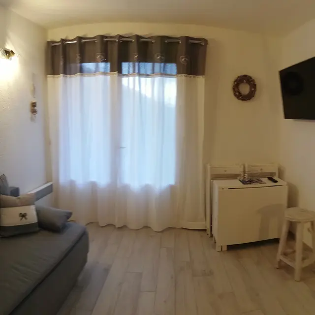 salon lumineux avec canapé, télévision, porte-fenêtre