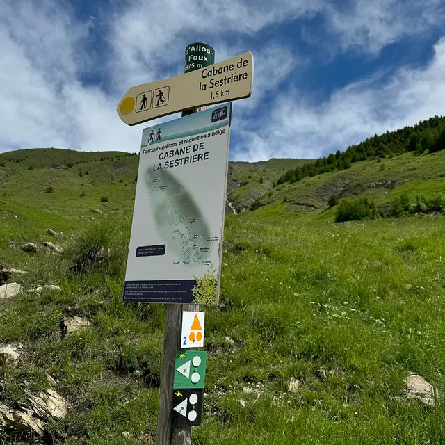 Panneau d'étape de l'itinéraire VTT AE des Sources du Verdon, situé au milieu d'un vallon de montagne verdoyant