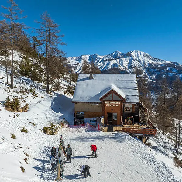 Vue du restaurant d'altitude, chalet en bois et pierre au milieu des montagnes enneigées, terrasse en bois