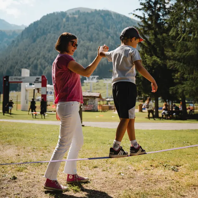 Slackline - maman qui aide un enfant en équilibre