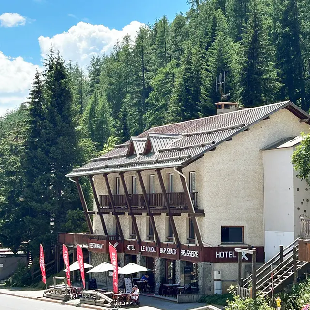 Vue de la brasserie sur 3 étages, bâtiment en pierre et bois avec terrasse en rdc et balcons