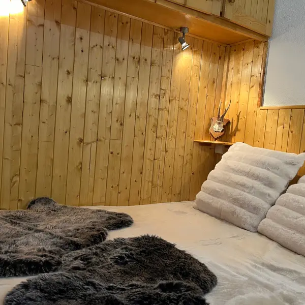 Chambre avec lit double, mur en lambris bois, placard en hauteur