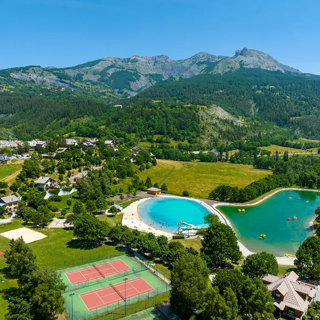 Parc de loisirs d'Allos depuis un point haut : deux grands bassins d'eau pour les pédalos et la baignade, dans un écrin de nature situé à côté du village. A côté des bassins, on trouve deux terrains de tennis, un terrain de volley-ball, et des jeux pour enfants