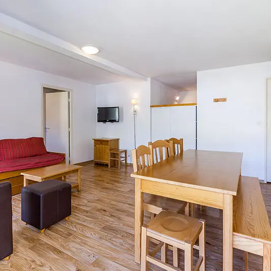 Séjour lumineux d'appartement avec canapé, fauteuil, table à manger, TV, séparations vers autres espaces