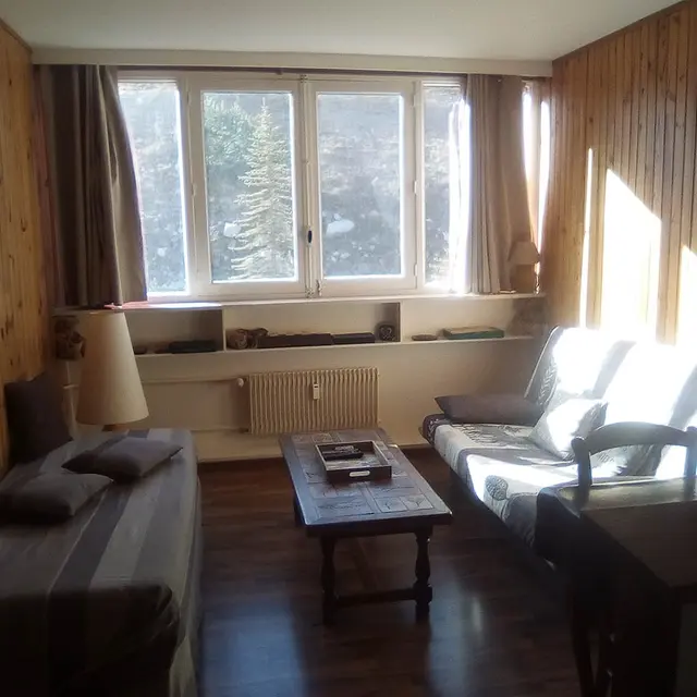 Séjour lumineux ameublement bois, lambris, fenêtre et rideaux