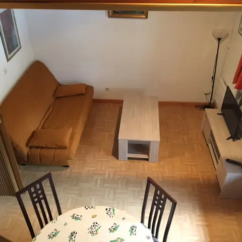 Séjour lumineux avec canapé, table à manger, table basse, TV, ameublement bois, parquet au sol, fenêtre