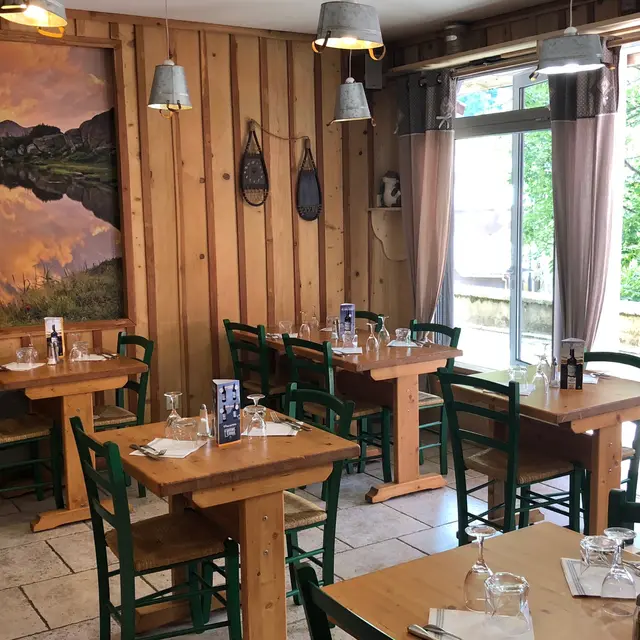 Salle de restaurant lumineuse avec décoration intérieur bois, tables et chaises assorties, tableau au mur, porte-fenêtre donnant sur la galerie marchande