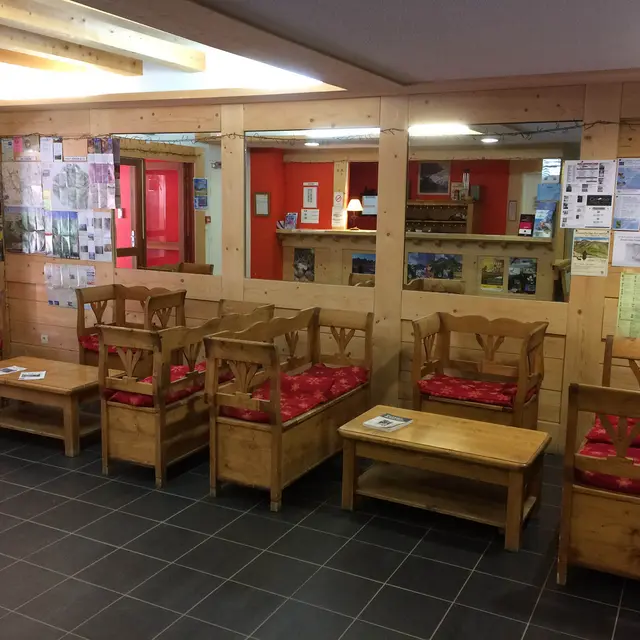 Hall d'entrée de la résidence, tables et chaises en bois, panneaux d'affichages, réception.