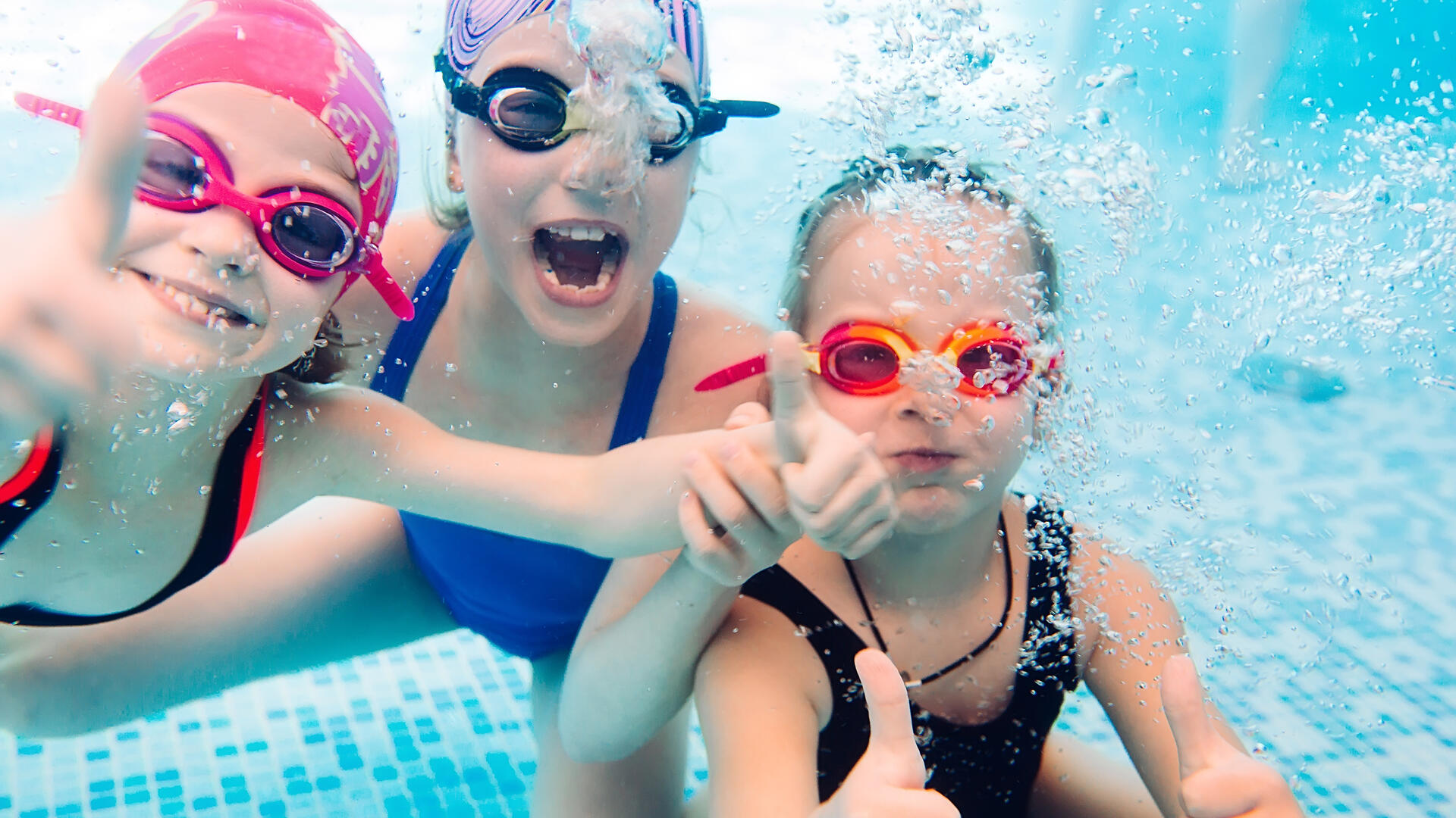 Underwater photo of young friends in swimming pool.